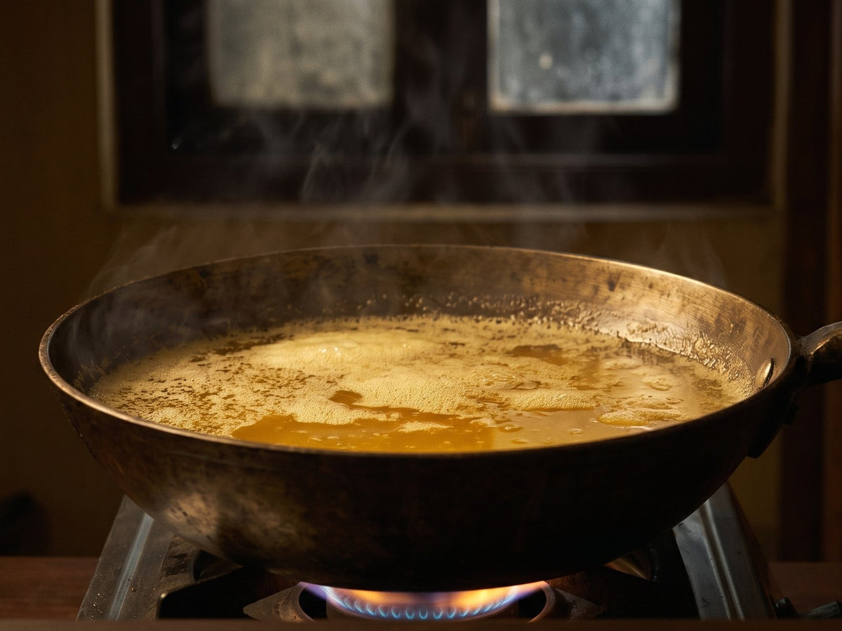Butter simmering into ghee in a heavy pan over a low flame